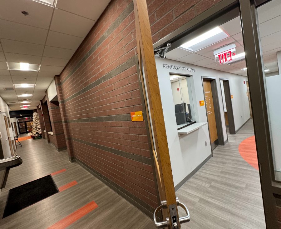 The hallway in Harbor House of Louisville leads directly to the medical area, with Kentucky Pharmacy prominently positioned as the first space inside this secure clinic area, visible immediately upon opening the door.